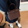 Mini brown matte leather crossbody tote bag shown on model in a retro style setting - Brown