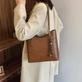 Retro brown faux leather tote bag with woven charm shown on model in minimal interior - Standard Type / Brown