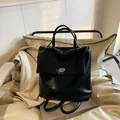 Mochila minimalista de cuero sintético negro con cierre plateado en una silla - Negro