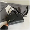 Detail of black faux leather handbag featuring a mini round coin purse and gold hardware - Black