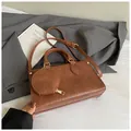 Close-up of brown leather handbag with a round coin purse and gold hardware detail - Brown