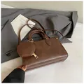 Detailed macro of brown retro crossbody bag with mini round coin purse and gold hardware - Brown