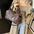 Borsa Boston marrone scuro con tracolla indossata su un trench kaki alla moda - Marrone
