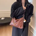 Borsa a secchiello in pelle opaca marrone con ciondolo da baseball su una modella - Marrone Caramello