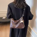 Secchiello in pelle marrone con cuciture bianche e ciondolo da baseball su una modella - caffè