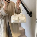 Schicke cremefarbene Schultertasche mit zwei Fronttaschen getragen zum beigen Trenchcoat - Weiß