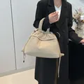 Quilted beige puffer tote bag with drawstring detail shown on a model in a minimalist room - Khaki