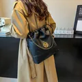 Sac seau noir à cordon avec chaîne dorée et logo M porté par un mannequin - Noir