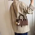 Braune Retro-Tragetasche mit Baseball-Anhänger von einem Model im Casual-Stil getragen - Standardtyp / Braun