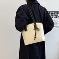 Sac cabas vintage crème avec anses marron foncé et charm à franges porté par mannequin - Blanc Cassé