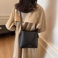 Minimalistische schwarze Beuteltasche mit Lychee-Textur und goldener Aufschrift - Schwarz