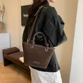 Dunkelbraune Wildlederbeutel-Tasche mit geknotetem Ledergriff und Maniroo-Details - Standard / Braun