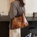 Minimalistische braune PU-Schultertasche mit dekorativer Schleife und großem Fassungsvermögen - Braun / 【produktmerkmale】das Kernprodukt Ist Eine Geräumige Braune Schultertasche. Das Material Wirkt Wie Weiches Pu-kunstleder Mit Natürlichem Glanz Und Lässigen Falten. Design-highlights Sind Die Schleife An Der Klappe Und Die Metallschnalle Die Der Tasche Einen Minimalistischen Koreanischen Stil Verleihen. 【visuelle Präsentation】die Bilder Wurden In Einem Realistischen Alltagsszenario Aufgenommen. Ein Model Trägt Die Tasche Vor Einem Hochwertigen Bar-hintergrund. Die Farbtemperatur Ist Harmonisch Und Die Braune Tasche Harmoniert Perfekt Mit Dem Grauen Anzug Wodurch Ein Starker Visueller Fokus Entsteht. Die Bildqualität Ist Hoch Mit Scharfen Details. Die Ästhetik Ist Mit 88 Punkten Sehr Gut Ohne Aufdringlich Zu Wirken Und Das Setting Unterstreicht Das Markenimage. 【textinhalte】alle Texte Sind `prop_text` (hand Made Auf Der Flasche Marshall Auf Dem Lautsprecher) Oder `product_text` (mikrotext Auf Den Beschlägen) Und Erfordern Keine Weitere Bearbeitung. 【logistik-etiketten】keine. 【risiko Von Markenrechtsverletzungen】das Produkt Selbst Weist Kein Erkennbares Markenlogo Auf Wodurch Die Wahrscheinlichkeit Einer Markenrechtsverletzung Bei 00 % Liegt. Obwohl Der Lautsprecher Im Hintergrund Das Marshall-logo Enthält Handelt Es Sich Dabei Um Ein Dekorationselement Das Keine Markenrechtsverletzung Darstellt. 【produktparameter】farbe: Braun; Material: Kunstleder; Typ: Große Schultertasche; Verzierung: Schleife.