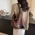 Large leopard print tote bag with cartoon design and leather straps in a cafe setting - Brown