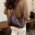 Borsa hobo bordeaux in pelle con catena d'argento mostrata in un ambiente di lifestyle - 25*8*21 / Rosso