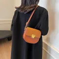 Borsa a sella marrone in finta pelle e camoscio con fibbia dorata su modella in cappotto nero - Grande / Marrone