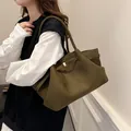 Sac fourre-tout en daim vert olive avec boucle latérale porté par un mannequin - Vert