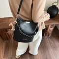 Schwarze gewebte Beuteltasche mit goldenen Details und Plüsch-Anhänger am Model - Schwarz