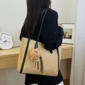 Sac cabas en daim beige avec bordure noire et breloque peluche porté par un mannequin - Daim Synthétique Tan