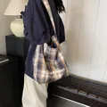 Brown blue plaid tote bag with white script text shown worn on the shoulder - Style 2 Blue Plaid (Our fave Party Print)
