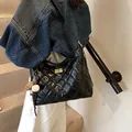 Borsa hobo nera trapuntata con finiture dorate e ciondoli indossata dalla modella - Nero