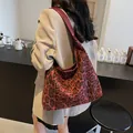 Große rote Tote-Bag mit Leopardenmuster und breitem Gurt in gemütlicher Café-Atmosphäre - Burgunderrot