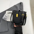Bolso tipo cubo negro con textura trenzada y detalles dorados sobre un fondo neutro - Negro