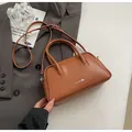 Minimalist brown bowling handbag with silver hardware on a chic grey blazer background - No Pendant / Caramel color