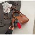 Brown leather bowling bag with vintage charms on a grey blazer background - With Pendant / Caramel color