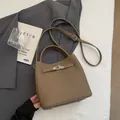 Borsa a secchiello in pelle marrone con chiusura a scatto argento su blazer grigio - Senza Ciondolo / caffè