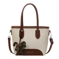 Bolso cubo de lona beige y cuero marrón con colgante de poni verde y correa ajustable - Dijes / Blanco Roto