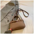 Brown litchi grain small square handbag with adjustable strap on grey blazer background - Coffee without Pendant