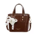 Borsa a secchiello lucida caramello con fiocco in pizzo e ciondolo a cuore di perle - Con Ciondolo / Marrone