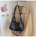 Detail of black hobo tote bag featuring knotted metal hardware and smooth leather texture - Black