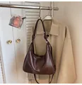 Detail of dark brown tote with glossy leather texture and stylish knot on the shoulder strap - Brown