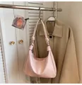 Detail of light pink hobo shoulder bag with knot strap hanging on a metal rack - Pink