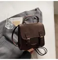 Detail der braunen Vintage-Ledertasche mit goldenen Beschlägen auf grauem Blazer - Standardausführung / Braun