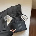 Minimalist black bucket bag with white contrast stitching and circular top handles - Black