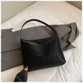 Classic black woven leather hobo bag with vintage texture shown in a lifestyle scene - Black