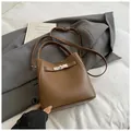 Borsa a secchiello marrone testurizzata con chiusura d'argento su blazer grigio scuro - Stile di base / Marrone
