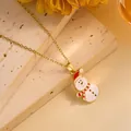 Macro shot of a cute snowman pendant with red hat on a gold necklace over a stone texture - Snowman