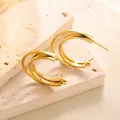 Detailansicht der dreischichtigen goldenen C-Form Ohrringe auf strukturiertem Naturstein - Gold