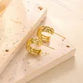 Dreilagige gewellte geometrische Titanstahl-Ohrstecker aus Gold auf beigem Travertin - Dreilagiger Gerippter Geometrischer Stil (ED044) / Gold