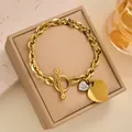 Detail eines goldenen Armbands mit OT-Verschluss, Zirkonia-Herz und poliertem Anhänger - Vollständiges Strassherz OT Armband / Gold