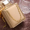 Elegant gold heart link necklace with sunburst engraving on a jewelry display - Necklace / Gold