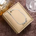 Macro detail of silver bow charm bracelet with flat snake chain in a jewelry box - Steel