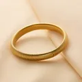 Elegante bracciale elastico Tubogas a spirale dorata su sfondo di seta morbida - Stile Elastico Larghezza 10mm / Oro
