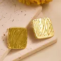 Detail von quadratischen Gold-Ohrsteckern mit 18K Wellenstruktur auf Natursteinplatte - Geprägter Quadratischer Stil (ED199)