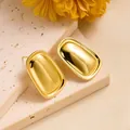 Detailed view of square gold earrings on a textured stone tray with yellow flowers - Smooth Trapezoid Style (ED220)