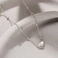 Elegant silver heart pendant necklace with fine bead chain on gray textured background - Steel